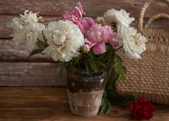 Still life with white and pink peonies in a old ceramic vase on wooden background