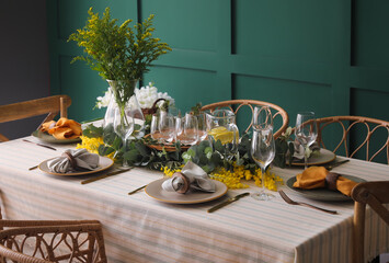 Dining table with beautiful setting near green wall