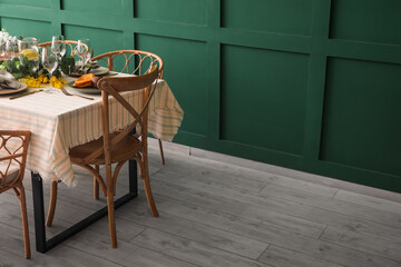 Dining table with beautiful setting near green wall