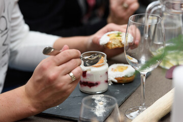 Woman eats dessert in a glass cup, with Jello, yogurt and topping served in a restaurant. Mini desserts