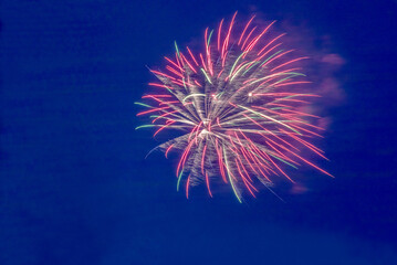 Festive bright urban multi-colored fireworks on a blue dark sky close-up.