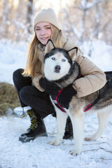 Dog husky breeds in winter on a snowy background. Blonde girl and dog. 