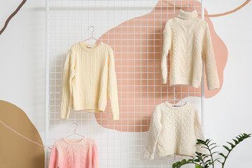 Children's sweaters hanging near color wall