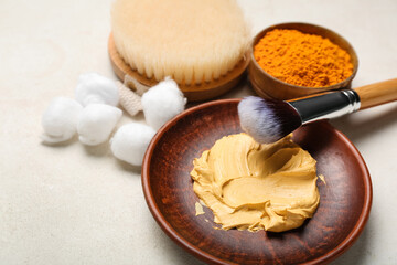 Plate with turmeric mask, powder and cotton balls on light background, closeup