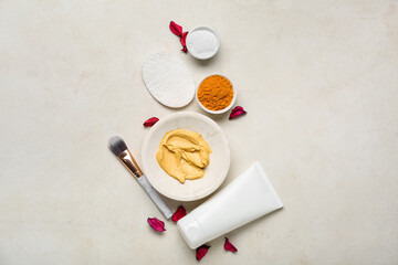 Composition with turmeric mask, powder and makeup brush on light background