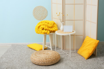 Interior of stylish room with rattan pouf, table and folding screen