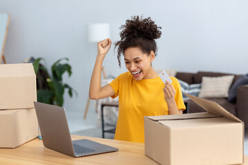 Portrait of beautiful Pleasantly excited African American woman shopping online, using laptop...