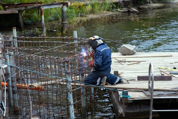 Welder in a protective mask assembles metal structures