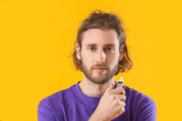 Handsome young man with vape mod on yellow background