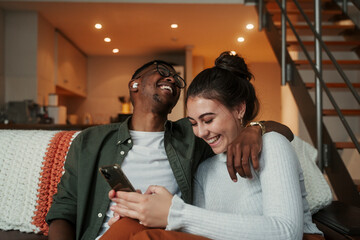 Biracial couple laughing while texting on cellular device
