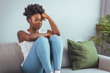 Unhappy lonely depressed woman at home, she is sitting on the couch and hiding her face on a...