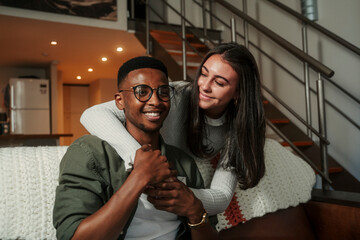 African American male and caucasian girlfriend showing affection on couch while hugging each other 
