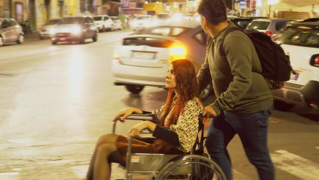 barriers, impediments-man pushes her friend in the wheelchair in the city 