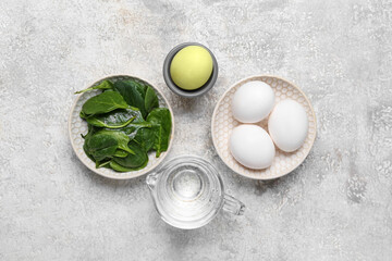 Bowl with natural dyed Easter eggs and spinach leaves on grunge background
