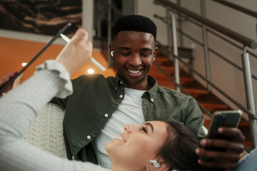 Biracial couple relaxing together on couch while using technology