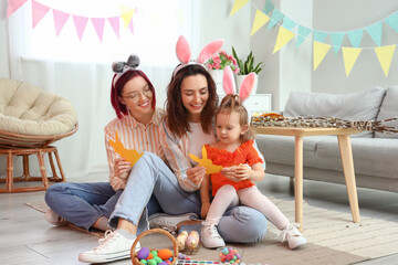 Young lesbian couple with little daughter at home on Easter eve