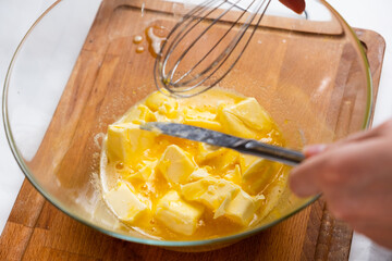 The dough preparation process. Female hands add butter into the mixing bowl for baking cake. Homemade recipe of pastry.