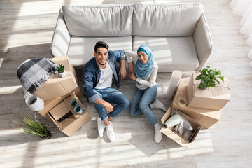 Top view of family sitting on floor among moving supplies