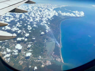 Arial shot of Gulf of Mexico coastline and blue water, with factory smoke billowing in the air and...