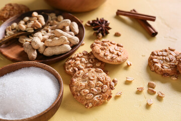 Tasty peanut cookies and sugar on yellow background