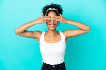 Fototapeta na wymiar Young latin woman isolated on blue background covering eyes by hands and smiling