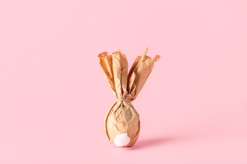 Egg wrapped in paper on color background. Easter celebration - obrazy, fototapety, plakaty
