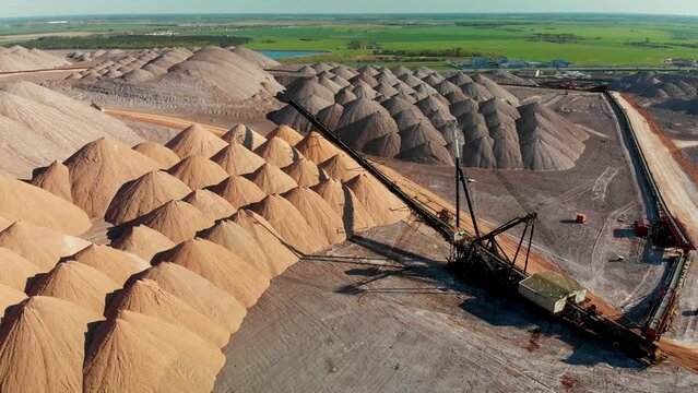 Mining industry close up. Telestacker handles the ore for potash waste heaps, extraction of salt and potash fertilizers in a quarry and processing of ore. Aerial fly around conveyour belt in Soligorsk
