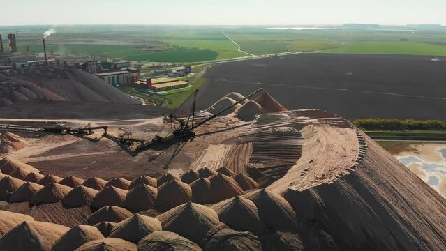 Mining industry close up. Telestacker handles the ore for potash waste heaps, extraction of salt and potash fertilizers in a quarry and processing of ore. Aerial fly towards conveyour belt