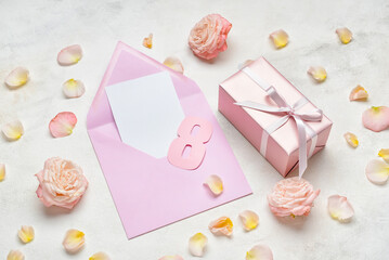 Composition with blank card, gift for International Women's Day and flowers on light background