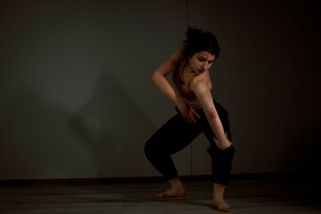 Slender flexible dance performer during a dance practice in modern studio