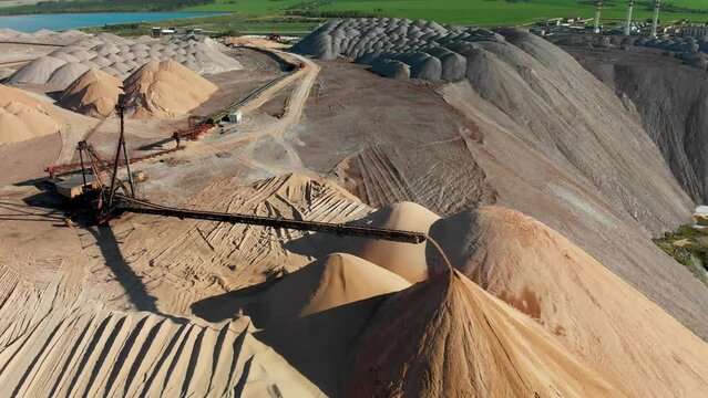 Aerial approaching giant conveyour belt that is making a hand-made mountains. Potash mining industry. 