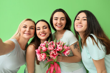 Beautiful women with flowers taking selfie on green background. International Women's Day...