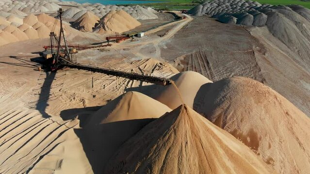 Aerial extra close up of working Telestacker with conveyour belt makes a pile of sand with salt and potash. Mining industry drone view. Potash from Soligorsk, Belarus sanctions.