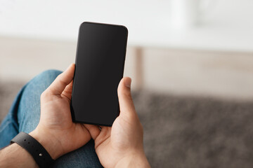 Mockup for website advertisement. Man using smartphone with blank screen, sitting at home, empty space, closeup