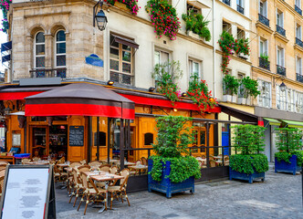 Fototapeta premium Typical view of the Parisian street with tables with tables of cafe in Paris, France. Architecture and landmark of Paris. Cozy Paris cityscape