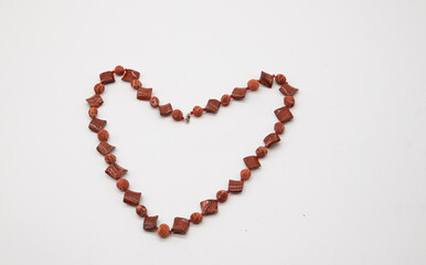 coral beads are laid out in the water of the heart on a white background