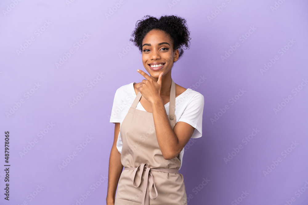 Poster Restaurant waiter latin woman isolated on purple background happy and smiling