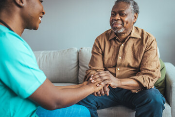 Male patient holding hands with a nurse. Nurse holding hand of senior man in rest home. Doctor helping old patient with Alzheimer's disease. Shot of a caregiver helping a senior man. - obrazy, fototapety, plakaty