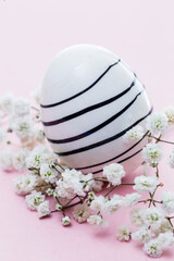 striped Easter egg with white flower on pink background