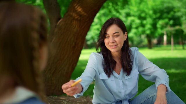 Mother giving bread stick to daughter close up. Family lunching on picnic