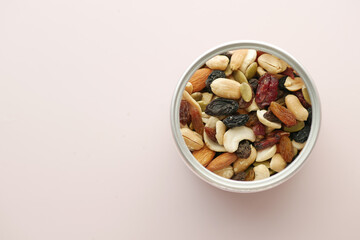 top view of many mixed nuts in a bowl on light purple background 