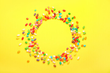 Frame made of different jelly beans on yellow background