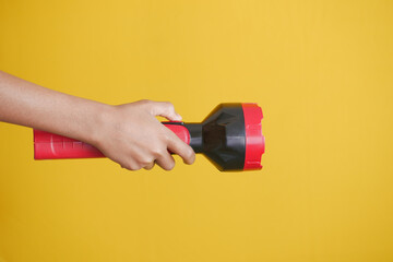 hand holding a tourch light against yellow background,