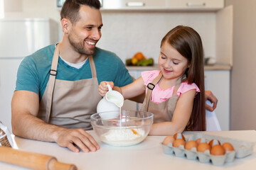Dad And Daughter Baking Cake Adding Milk To Dough Indoor