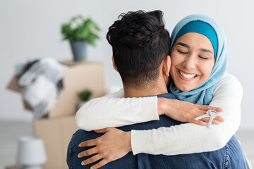 Happy lady in hijab with keychain hugging her husband