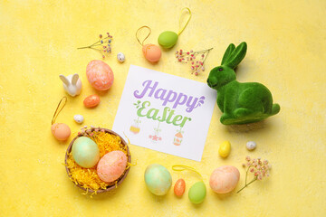 Beautiful Easter composition with greeting card, painted eggs, bunny and flowers on color background