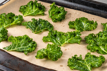 Kale chips on a baking sheet on parchment.
