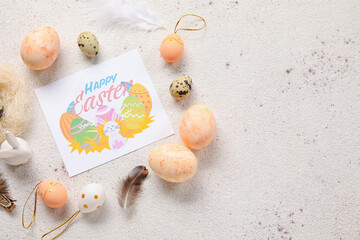Beautiful composition with greeting card, Easter eggs and feathers on light background
