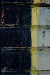 Old black yellow paint with cracks on wall as background, texture, selective focus