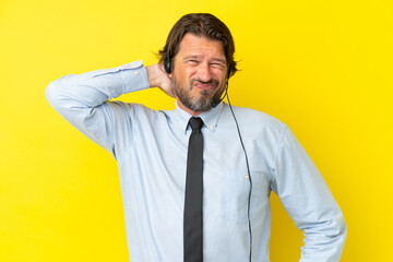 Telemarketer dutch man working with a headset isolated on yellow background with neckache